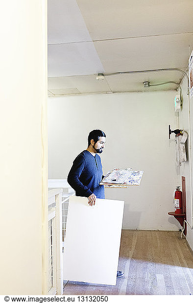 Painter carrying paintings in art studio