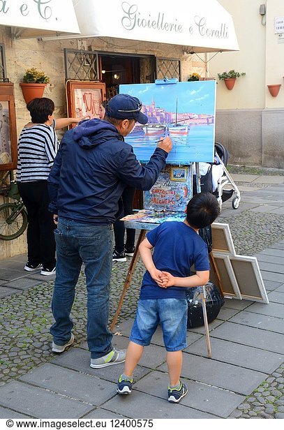 Painter in the old town of Alghero  Sardinia  Italy. A little boy looks on.