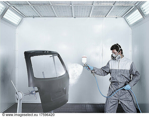 Painter spray painting door at repair shop