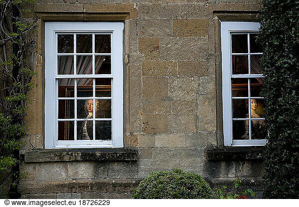 Paintings peer out through the window of a Fine Art Gallery in Broadway  England.