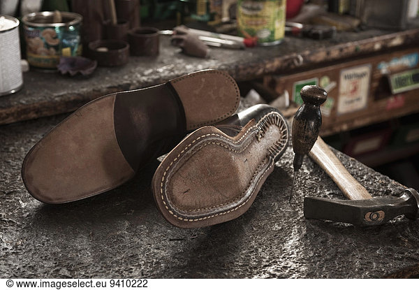 Pair of leather shoes  awl and hammer in a cobbler's shop