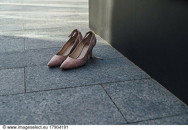 Pair of pink shoes on footpath
