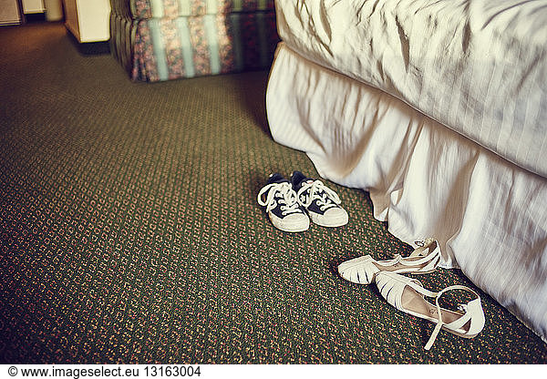Pair of trainers and sandals on bedroom carpet