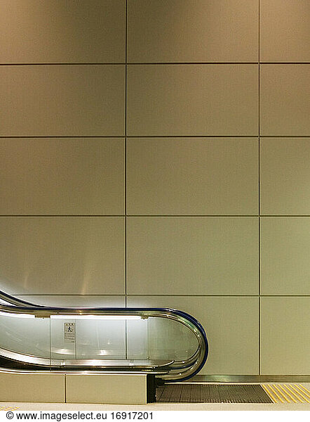 Panelled wall behind escalator in airport.