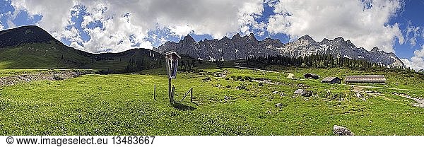Panorama at the Ladizalm alipine pasture with Lalidererwaende Cliffs  wayside cross  hikers  meadows and clouds in the Karwendel Range  Tyrol  Austria  Europe