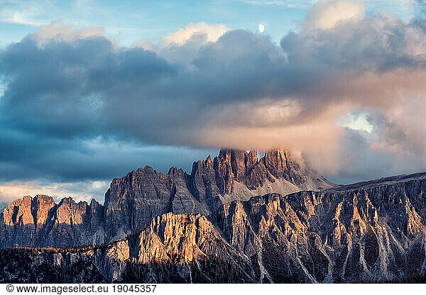 Panorama of high rocky mountains at cloudy sunset