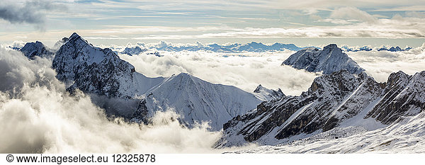 Panorama of snow-covered mountain peaks with cloud cover exposing peaks; Grainau  Bavaria  Germany