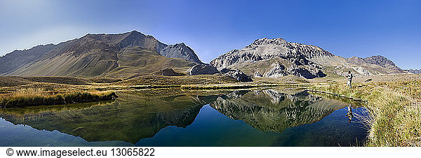 Panoramic view of lake by mountain against clear blue sky