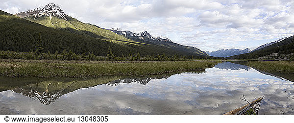 Panoramic view of lake by mountains against cloudy sky