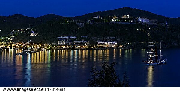Panoramic view of Porto Azzurro with illuminated harbour promenade in evening mood during blue hour  top right in the background Casa di Reclusione House of Detention  Porto Azzurro  Elba  Tuscany  Italy  Europe