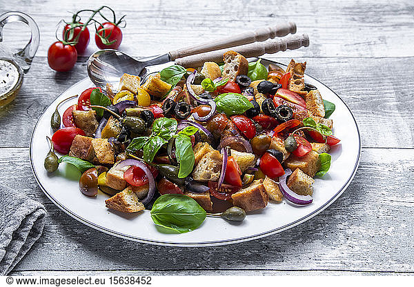 Panzanella  Italian bread salad with roasted ciabatta  tomatoes  olives  red onion  caper apples and basil on plate