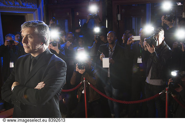 Paparazzi using flash photography behind bodyguard at red carpet event
