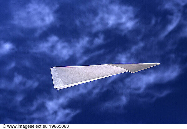 Paper airplane flying against blue sky.