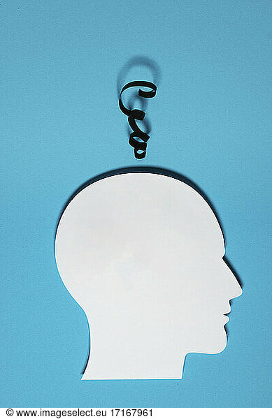 Paper cutout of human head with piece of string representing thoughts