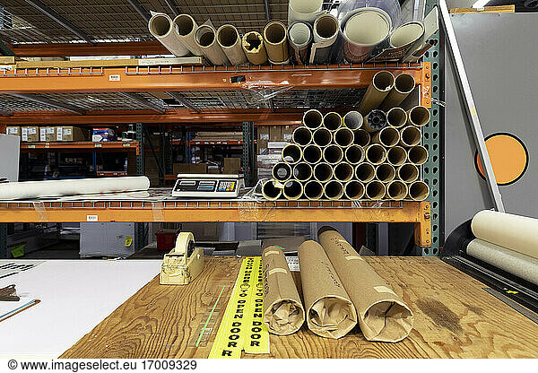 Paper rolls on workbench against rack in print shop