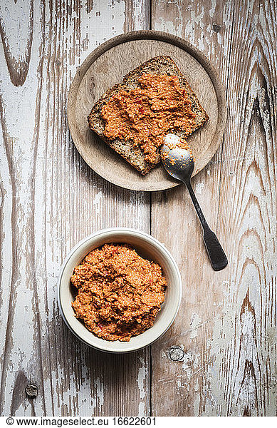 Paprika and sesame spread bowl by slice of bread on table