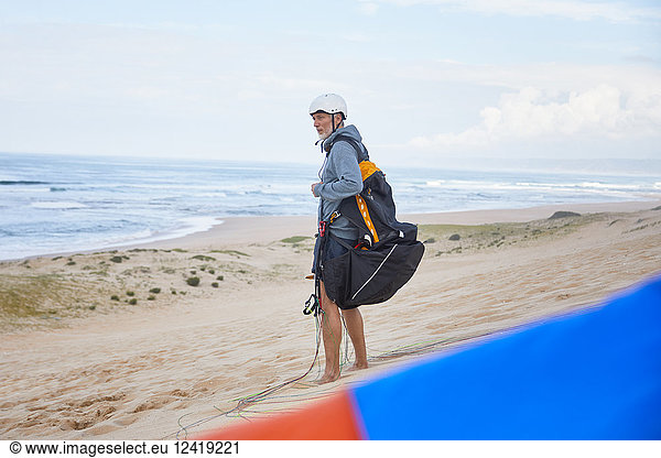 Paraglider with parachute backpack on ocean beach