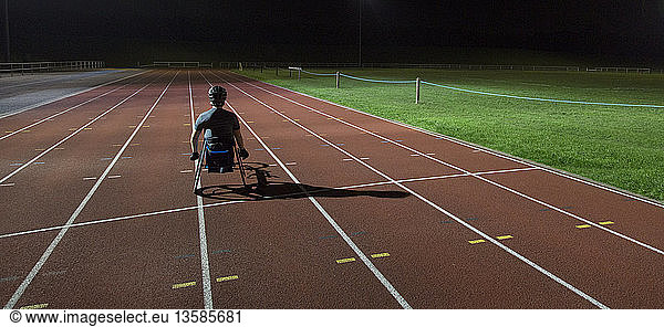 Paraplegic athlete training for wheelchair race on sports track at night