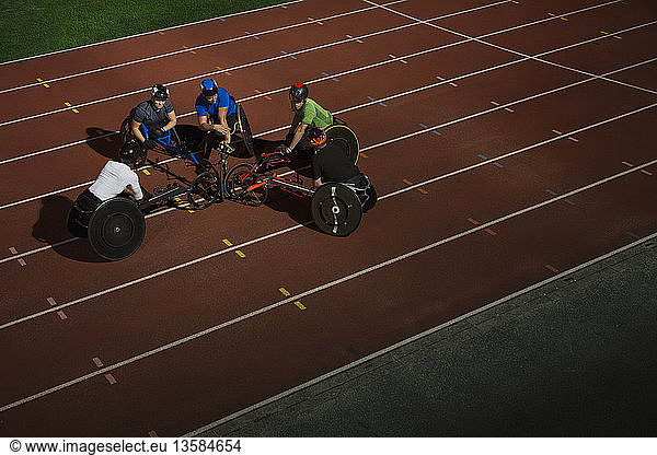Paraplegic athletes huddling on sports track  training for wheelchair race