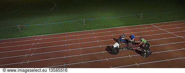 Paraplegic athletes huddling on sports track  training for wheelchair race at night