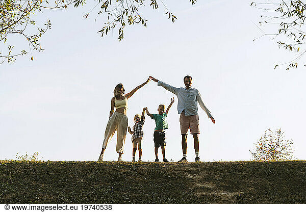 Parents and children standing with arms raised in park