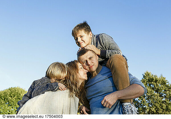 Parents carrying sons on sunny day