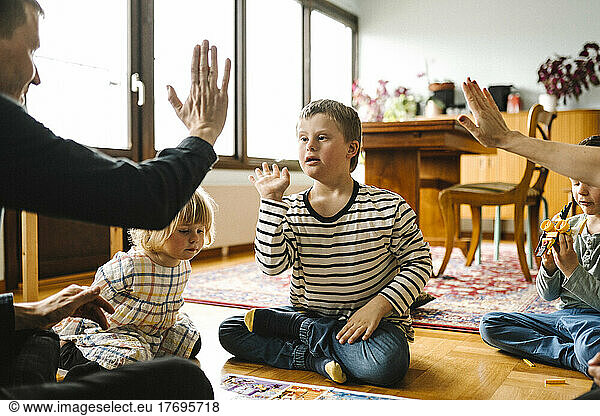 Parents doing high-five with son having down syndrome sitting in living room at home