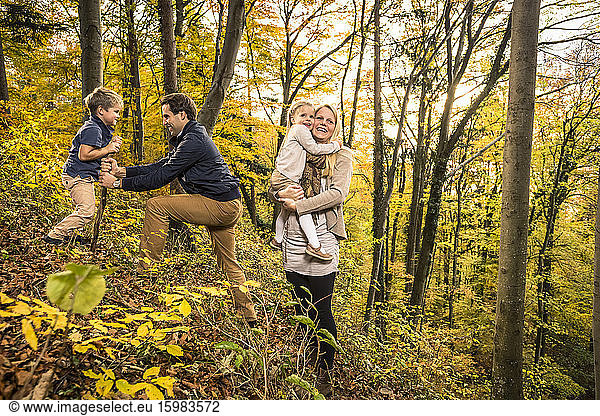 Parents enjoying with children in forest during autumn