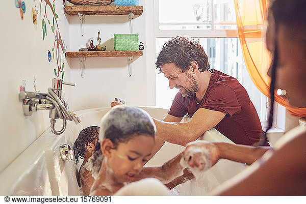 Parents giving toddler daughters bubble bath