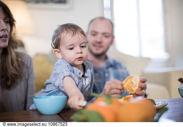 Parents having lunch with baby boy  peeling orange