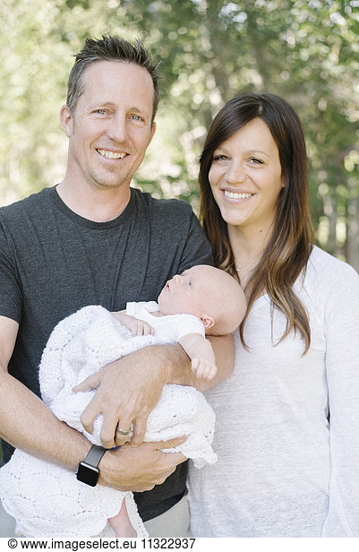 Parents holding a small baby  a group portrait.