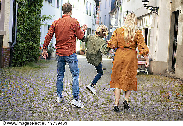 Parents holding hands and lifting son on alley