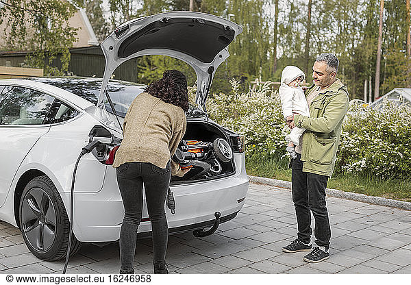 Parents loading pram into car boot