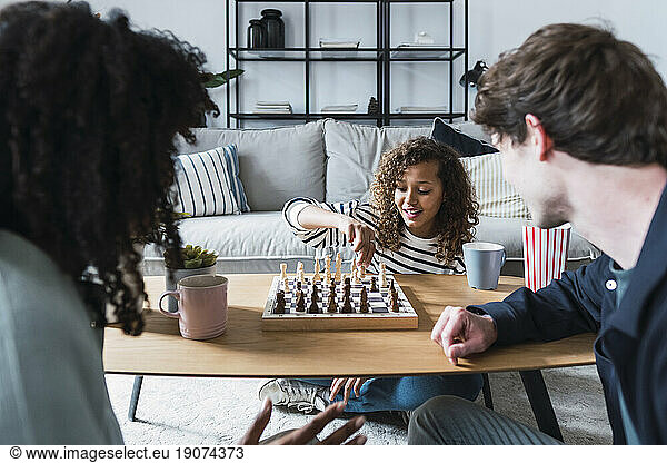Parents sitting in livingroom teaching daughter to play chess