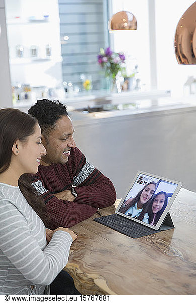 Parents video conferencing with daughters at digital tablet