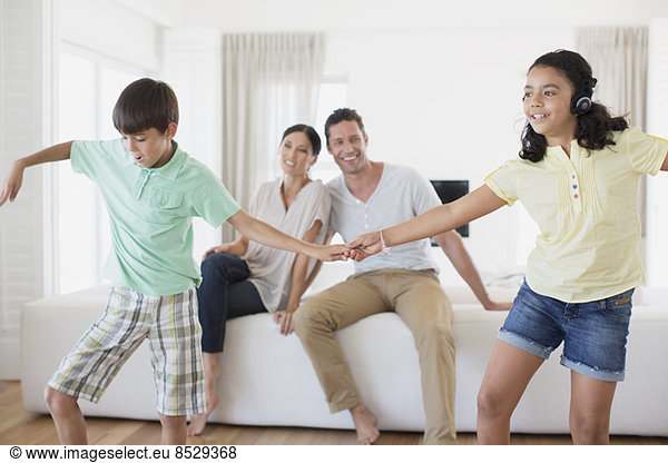 Parents watching daughter and son dancing in living room
