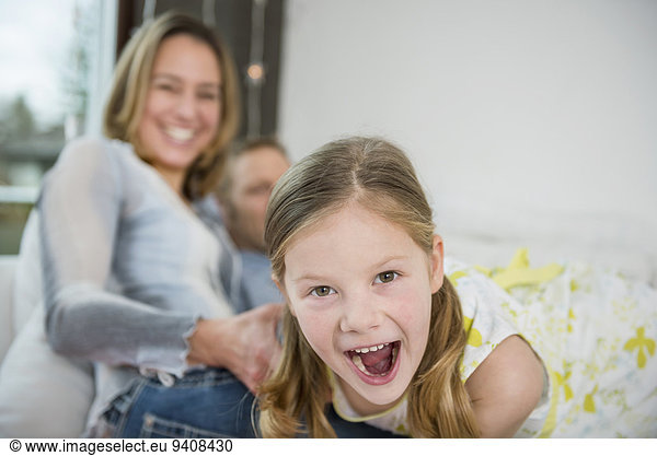 Parents with daughter sitting on couch having fun