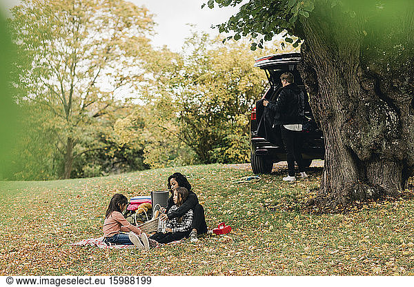 Parents with daughters enjoying picnic during autumn