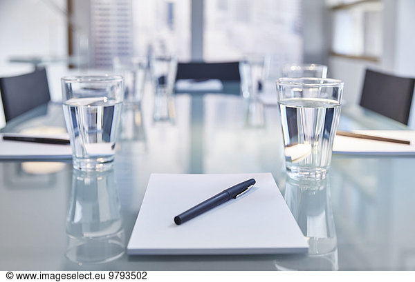 Part of modern conference room with table chairs  notepads  pens and glasses with water