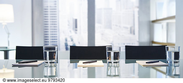 Part of modern conference room with table chairs pens and glasses with water