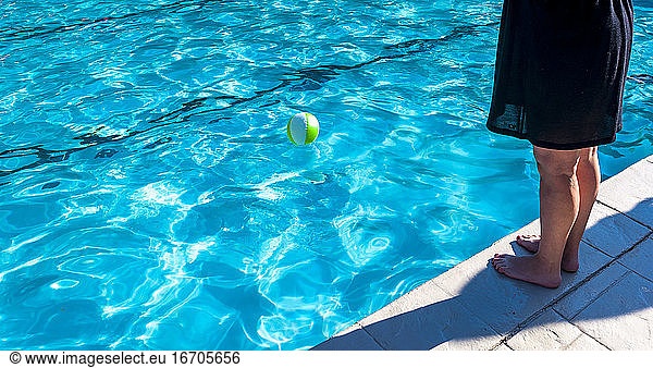 Partial view of a woman's legs standing by the edge of a swimming pool