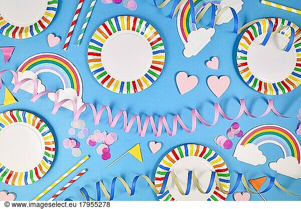 Party flat lay with colorful plates  rainbow napkins and drinking straws on blue background