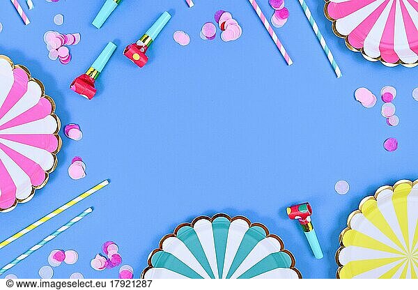 Party flat lay with paper plates  drinking straws and confetti on blue background with copy space