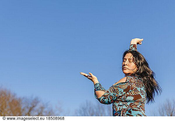 Passionate portrait of woman dancing against blue sky