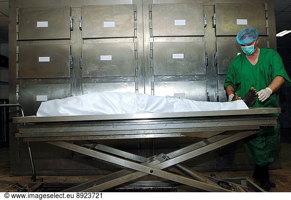 Pathologist inspecting the feet and legs of a corpse.