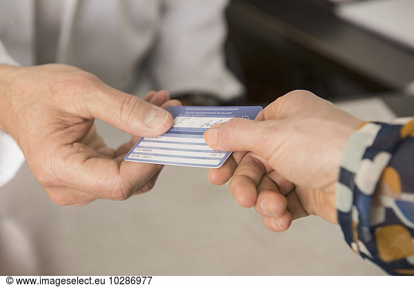 Patient giving a health insurance card to doctor  Munich  Bavaria  Germany