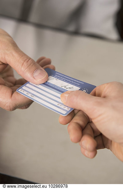 Patient giving a health insurance card to doctor  Munich  Bavaria  Germany