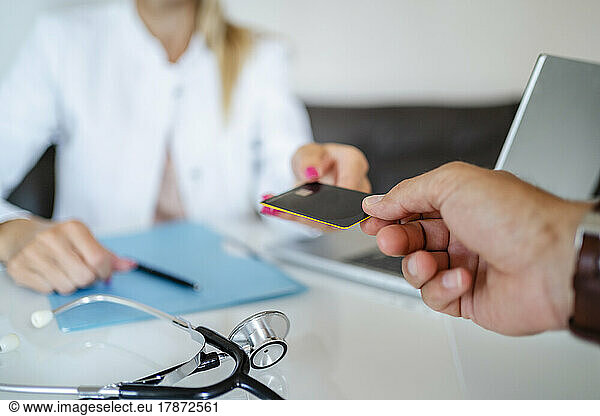 Patient handing over card to doctor in medical practice