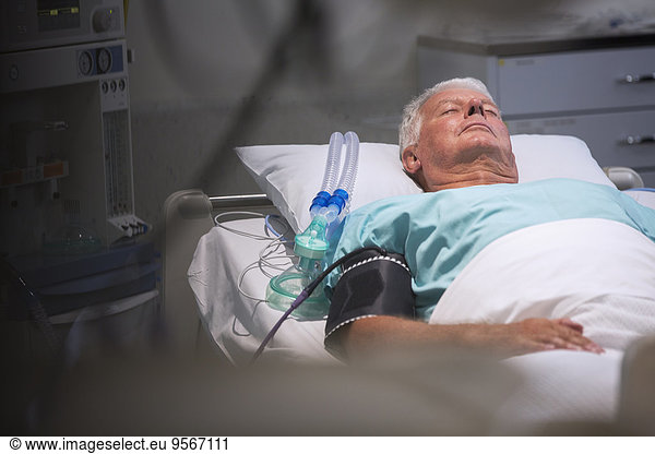 Patient lying in bed next to oxygen mask in intensive care unit