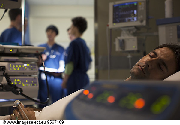 Patient surrounded by medical monitoring equipment in intensive care unit